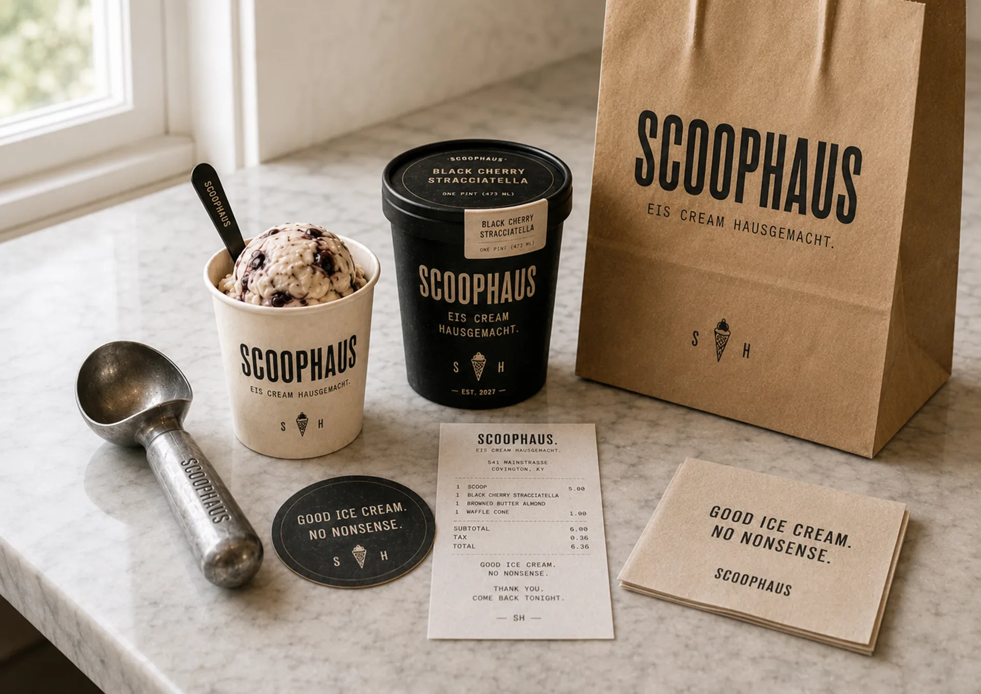Scoophaus takeaway kit with white cup, black pint, kraft bag, scoop, receipt, and printed card