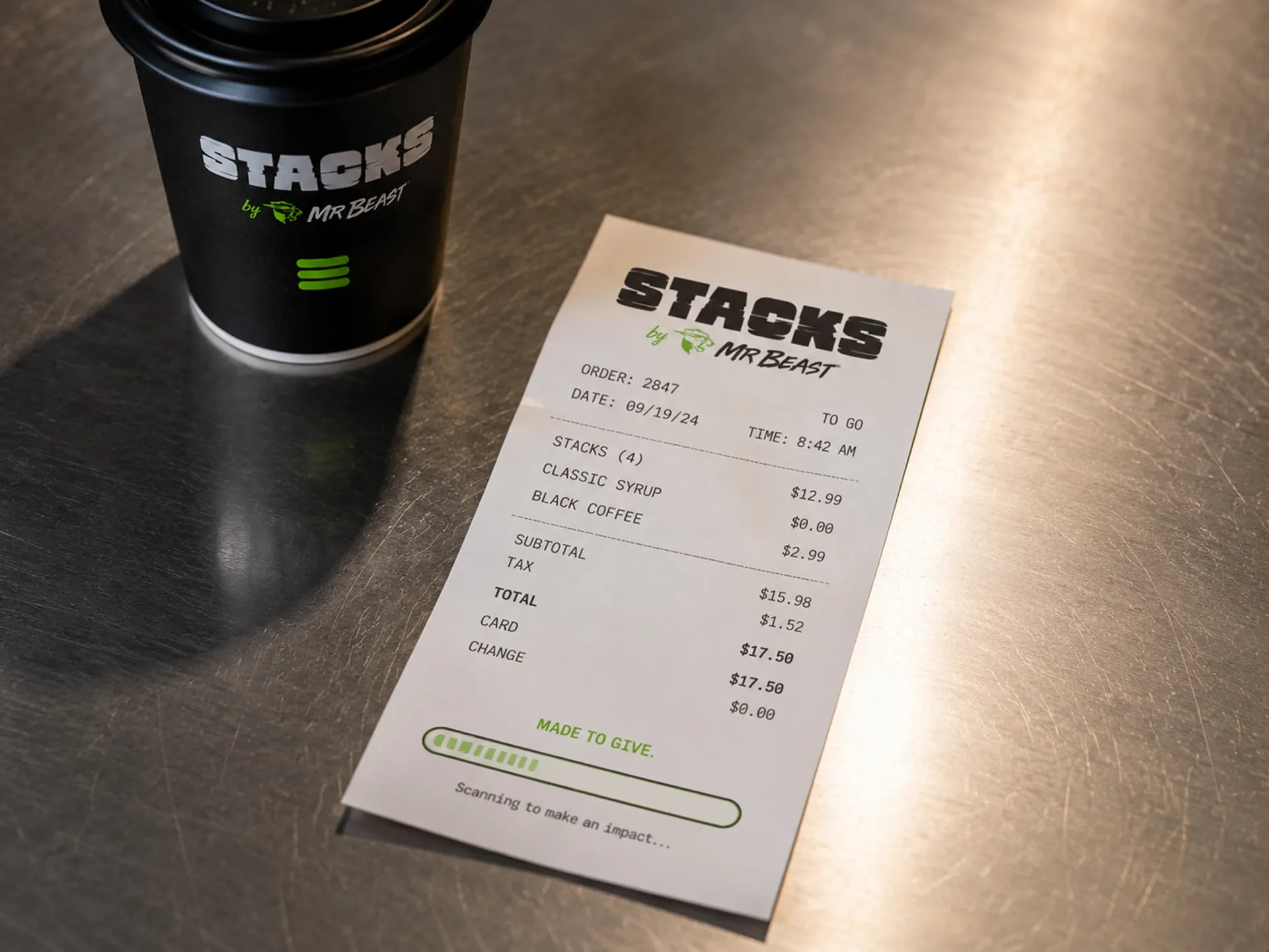 Stacks receipt detail beside a black branded coffee cup on a metal counter