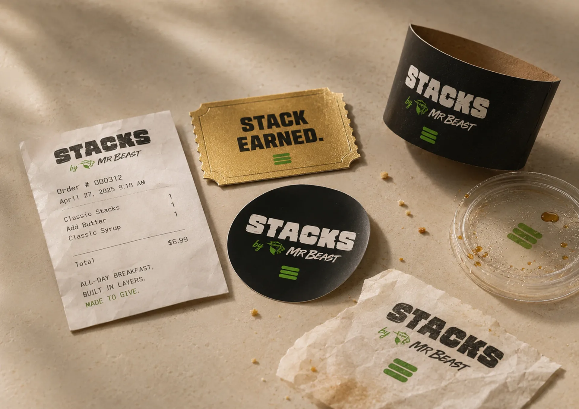 Stacks receipt, Stack Earned ticket, branded coaster, black cup, and wrap paper on a tabletop