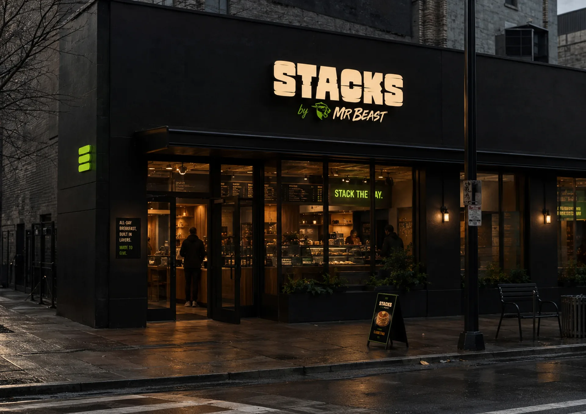 Stacks by MrBeast storefront at night with black facade, glowing sign, pickup window, and sidewalk board