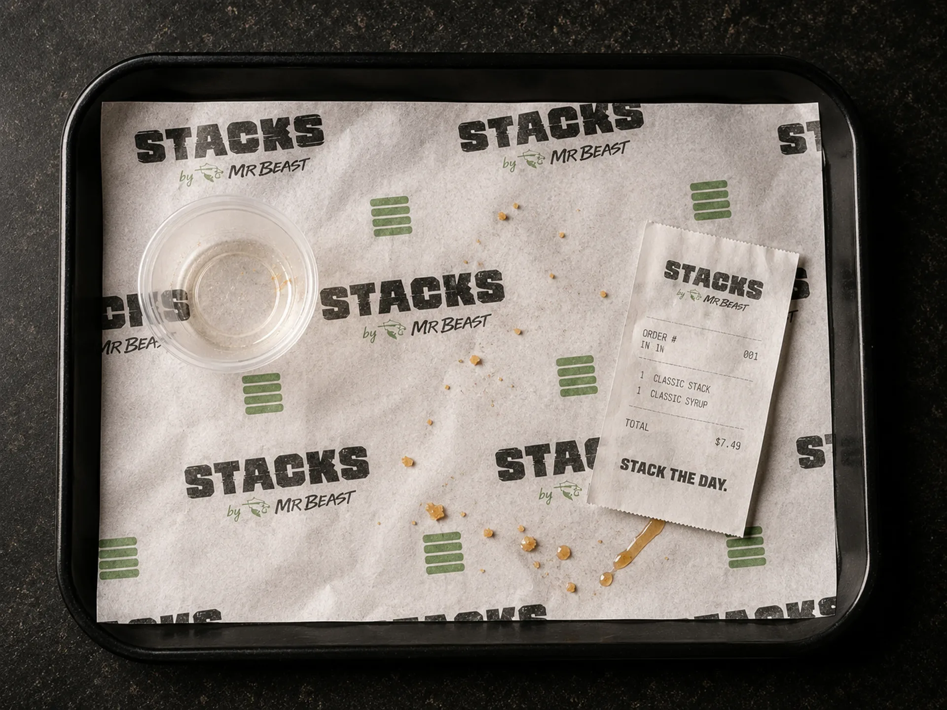Stacks branded wrap paper, sauce cup, and receipt on a black service tray