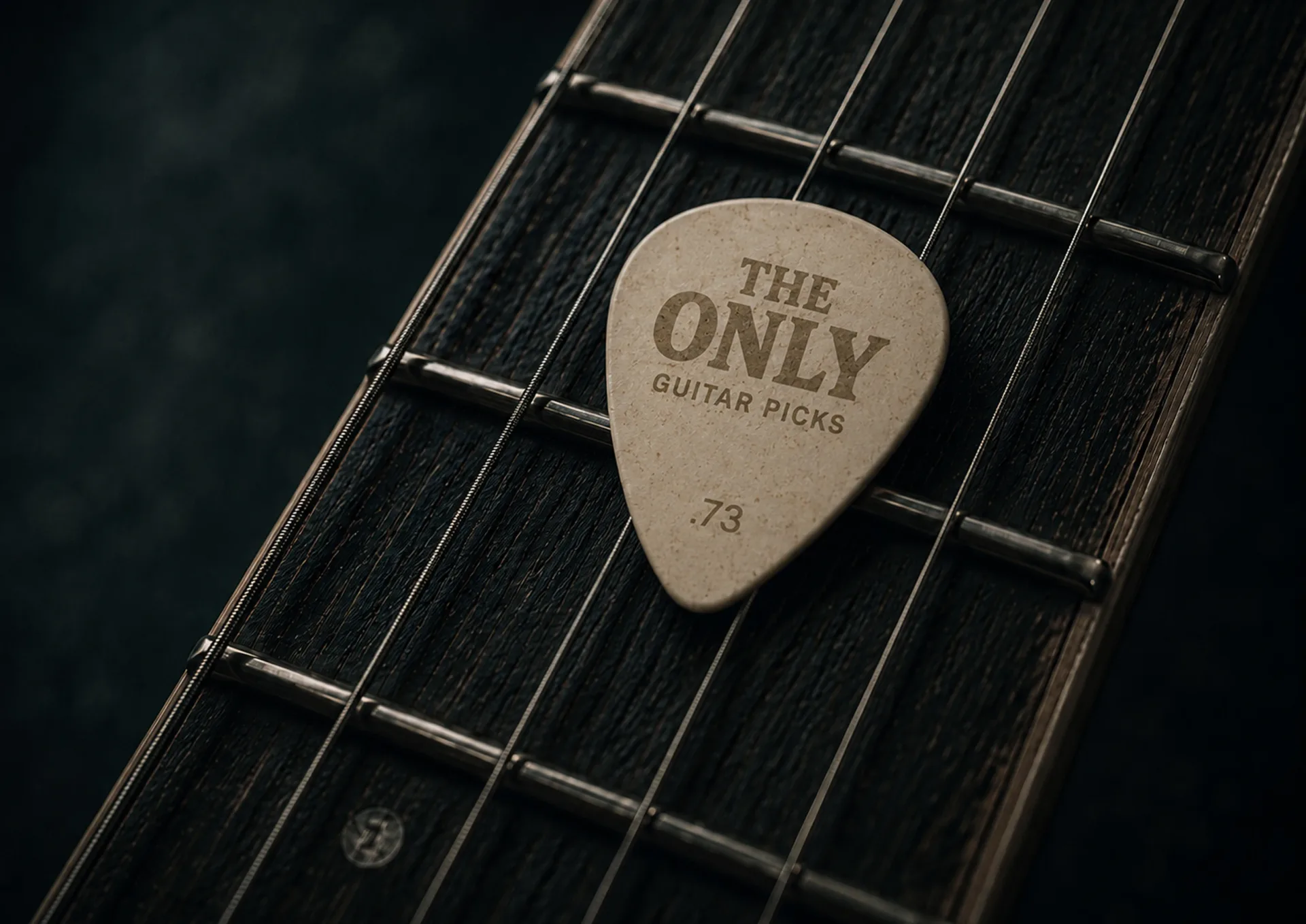 The Only guitar pick close-up on a dark guitar fretboard